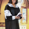 A  senior-adult woman in her black and white pastoral robe inside an old English Gothic church.